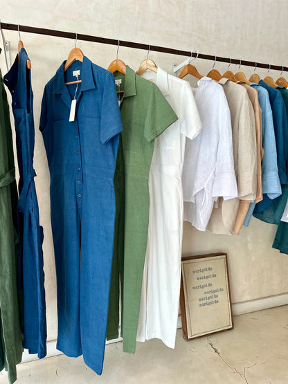 Collection of colorful playsuits hanging on a rack with a neutral background.