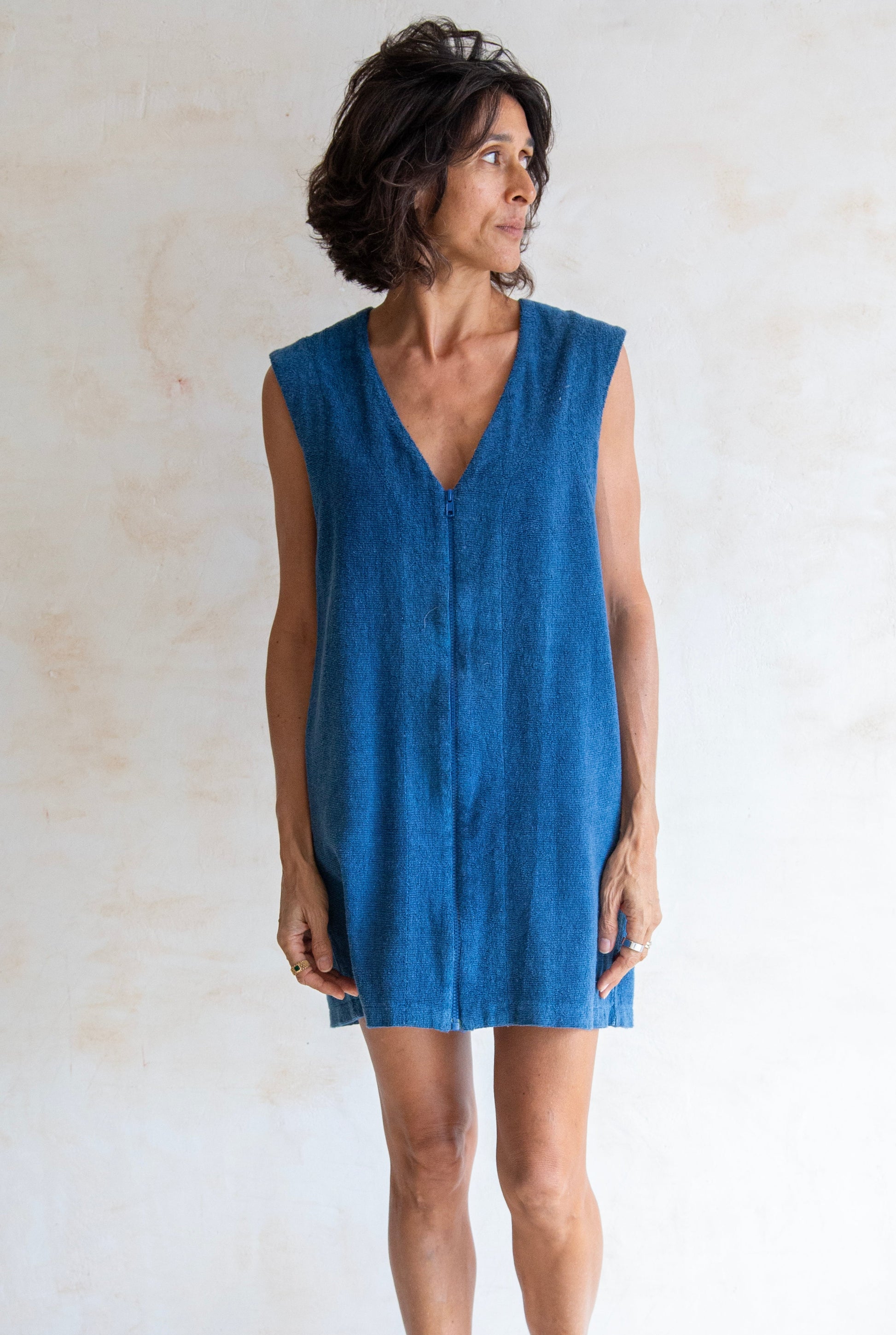 Woman wearing a blue sleeveless dress against a plain background