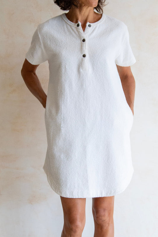 Woman wearing a white dress standing against a plain background